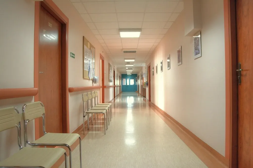 An empty hospital corridor with waiting chairs.