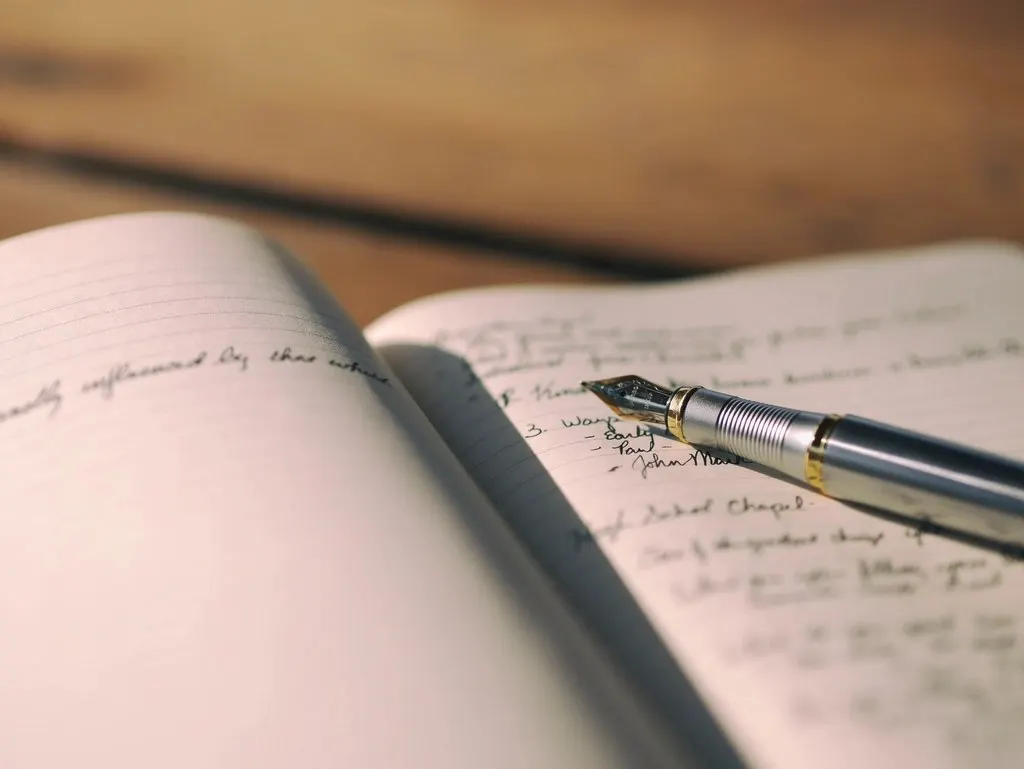 A fountain pen resting on an open handwritten journal.